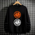 Black crewneck sweatshirt featuring two vertically stacked circular Dragon Ball Z 'Go' Kanji symbols (one orange, one white), flat lay on grey background.