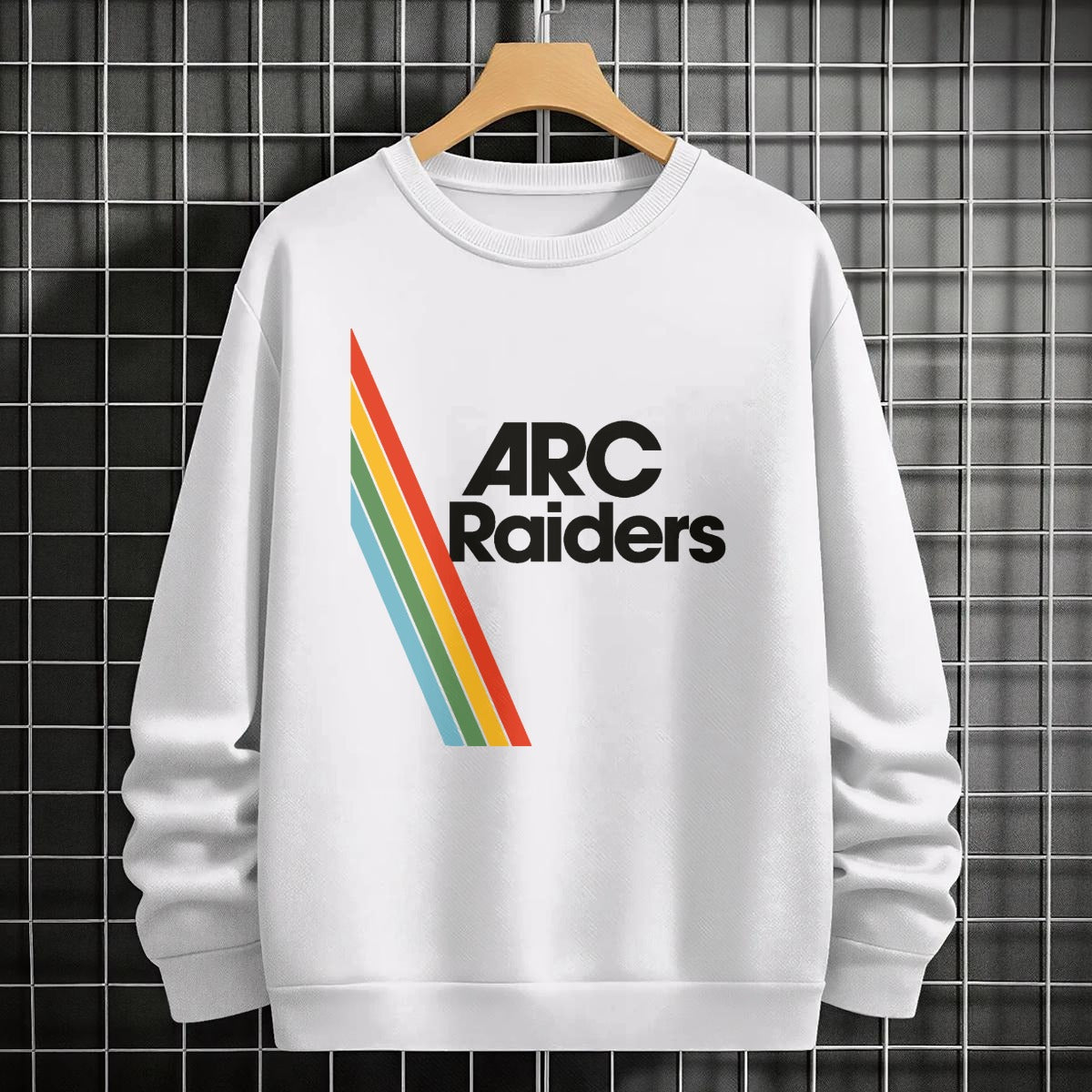 White sweatshirt with 'ARC Raiders' logo on a hanger against a tiled wall.