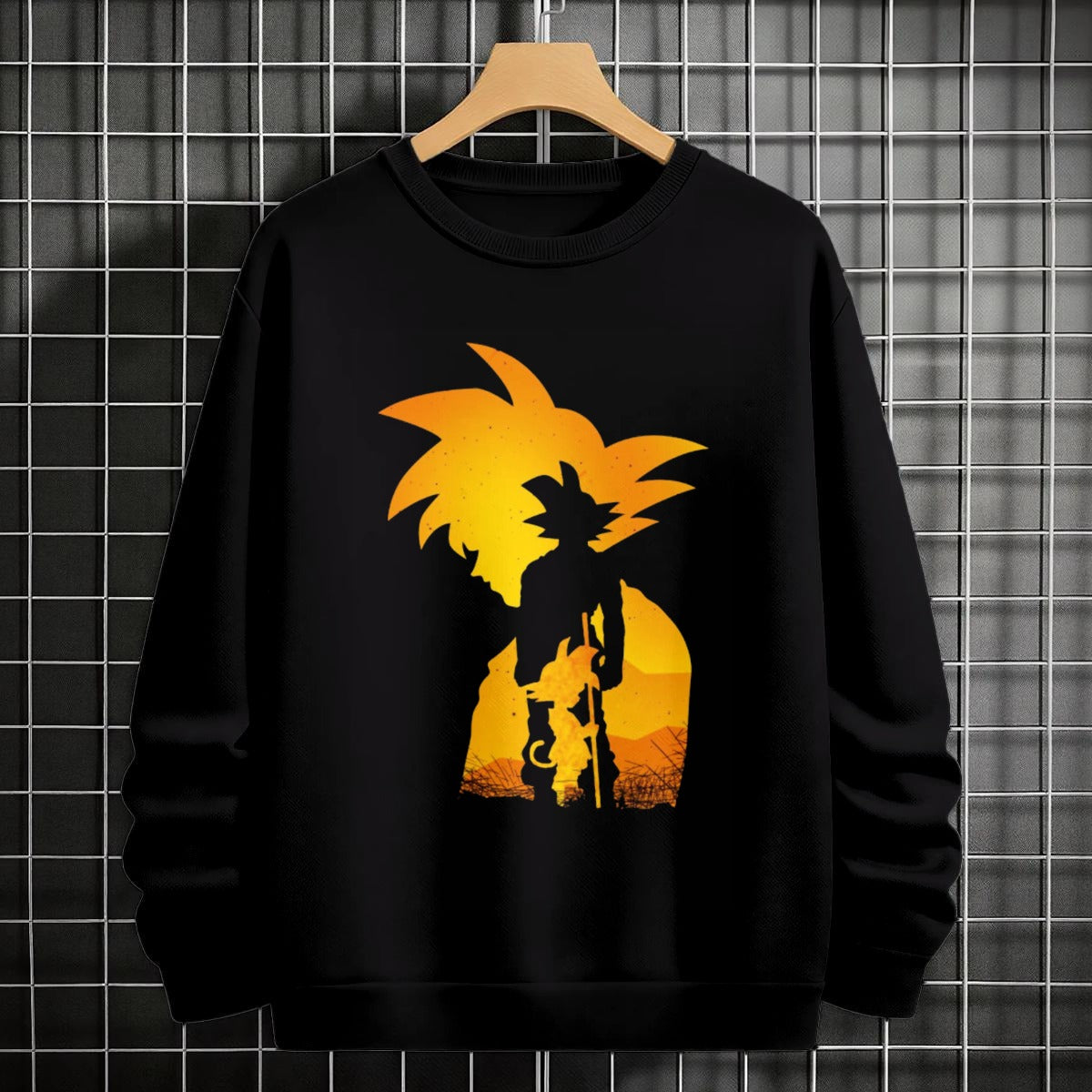 Black crewneck sweatshirt featuring Goku shadow silhouette with blue and pink neon aura and vertical Japanese text, flat lay on grey background.