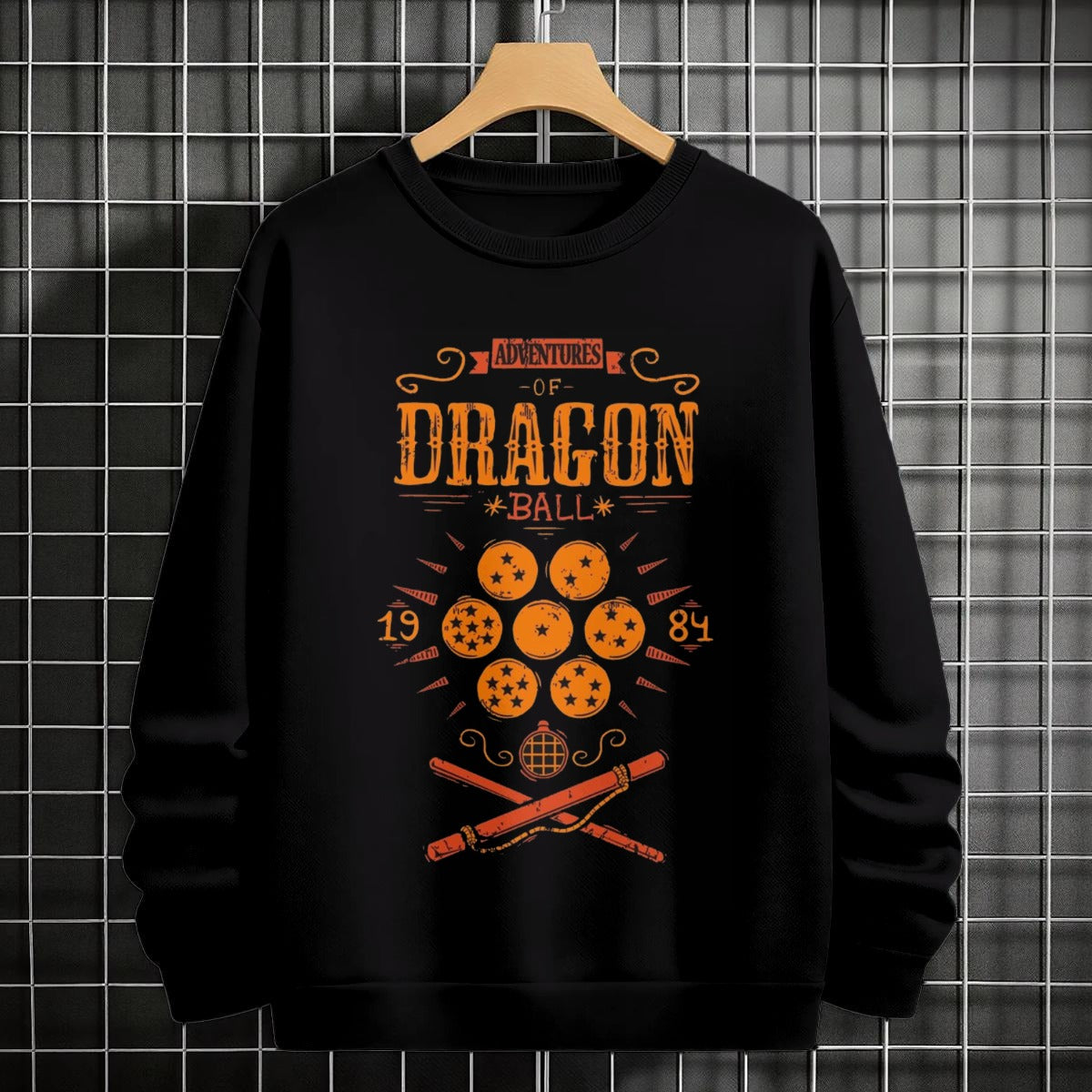 Black crewneck sweatshirt featuring Goku shadow silhouette with blue and pink neon aura and vertical Japanese text, flat lay on grey background.