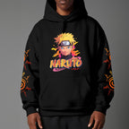 Black pullover hoodie featuring Naruto Uzumaki portrait on chest and vertical orange Japanese Kanji text on sleeves, worn by model on grey background.