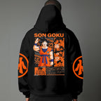 Black pullover hoodie with orange Goku silhouette on chest and vintage 1984 Dragon Ball graphics on sleeves, worn by model on grey background.