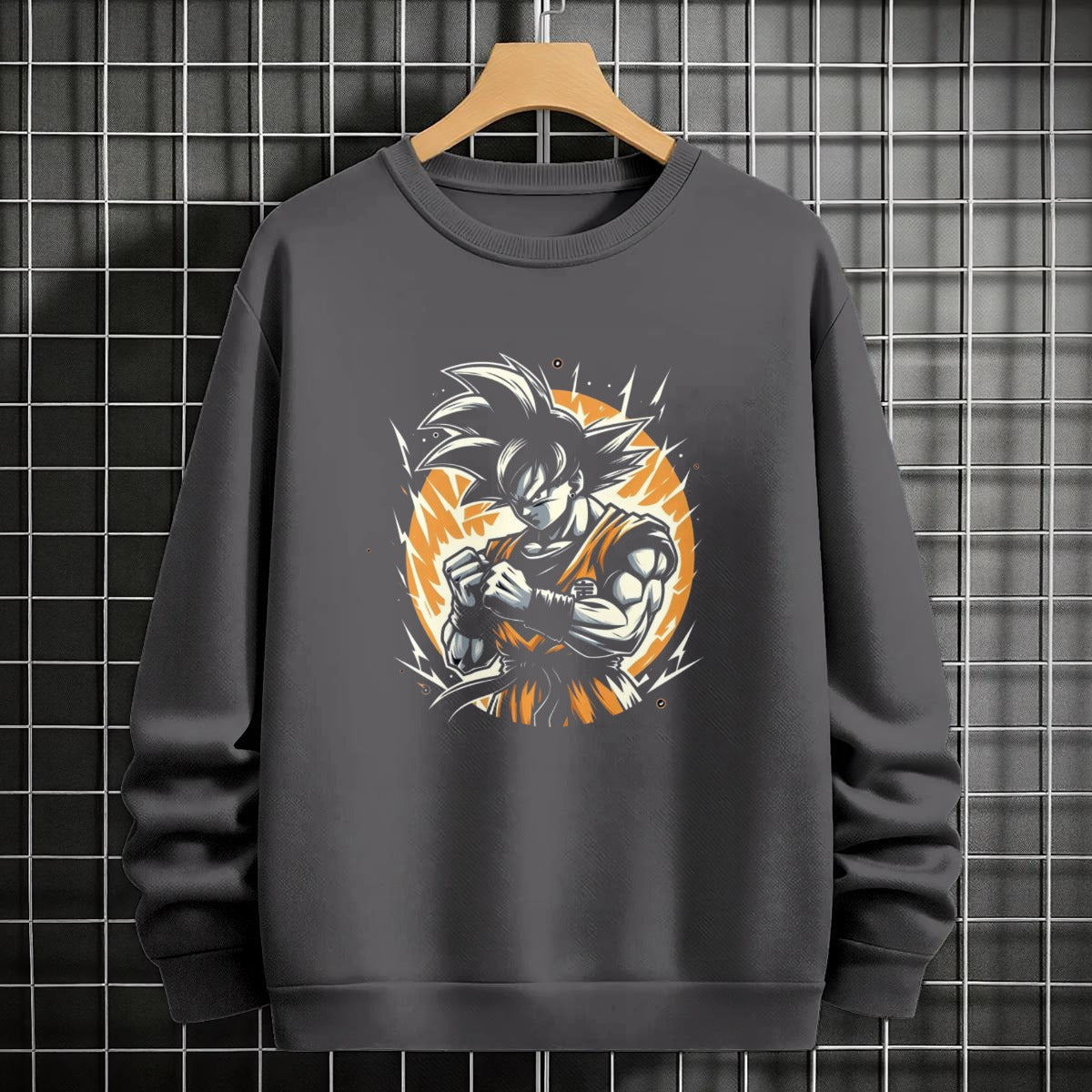 Black crewneck sweatshirt featuring Goku shadow silhouette with blue and pink neon aura and vertical Japanese text, flat lay on grey background.