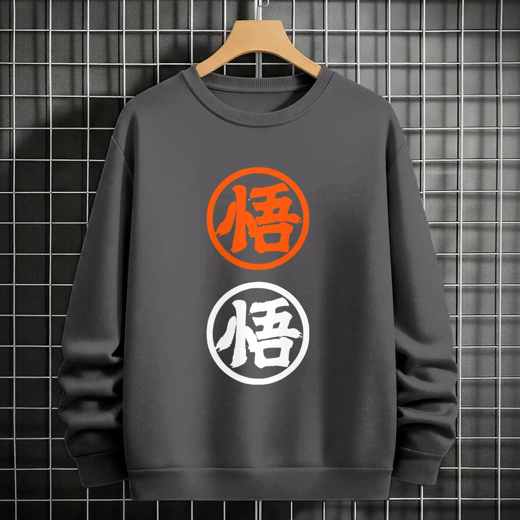Black crewneck sweatshirt featuring two vertically stacked circular Dragon Ball Z 'Go' Kanji symbols (one orange, one white), flat lay on grey background.