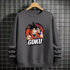 Black crewneck sweatshirt featuring Goku shadow silhouette with blue and pink neon aura and vertical Japanese text, flat lay on grey background.
