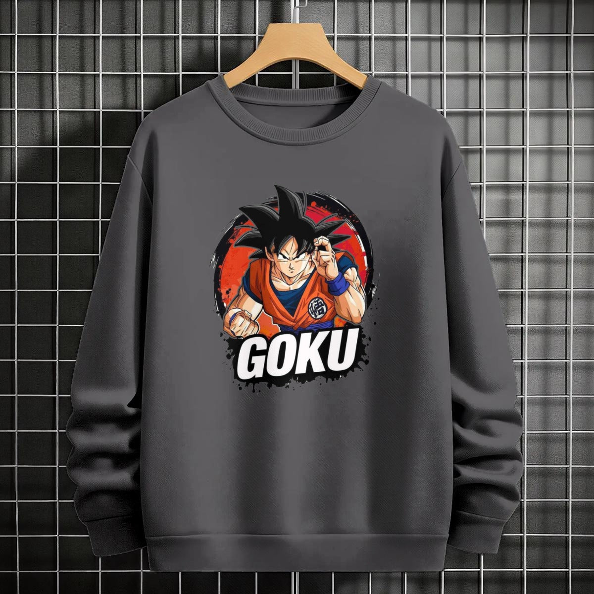 Black crewneck sweatshirt featuring Goku shadow silhouette with blue and pink neon aura and vertical Japanese text, flat lay on grey background.