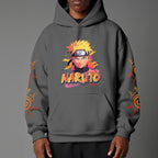 Black pullover hoodie featuring Naruto Uzumaki portrait on chest and vertical orange Japanese Kanji text on sleeves, worn by model on grey background.