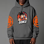 Black pullover hoodie with orange Goku silhouette on chest and vintage 1984 Dragon Ball graphics on sleeves, worn by model on grey background.