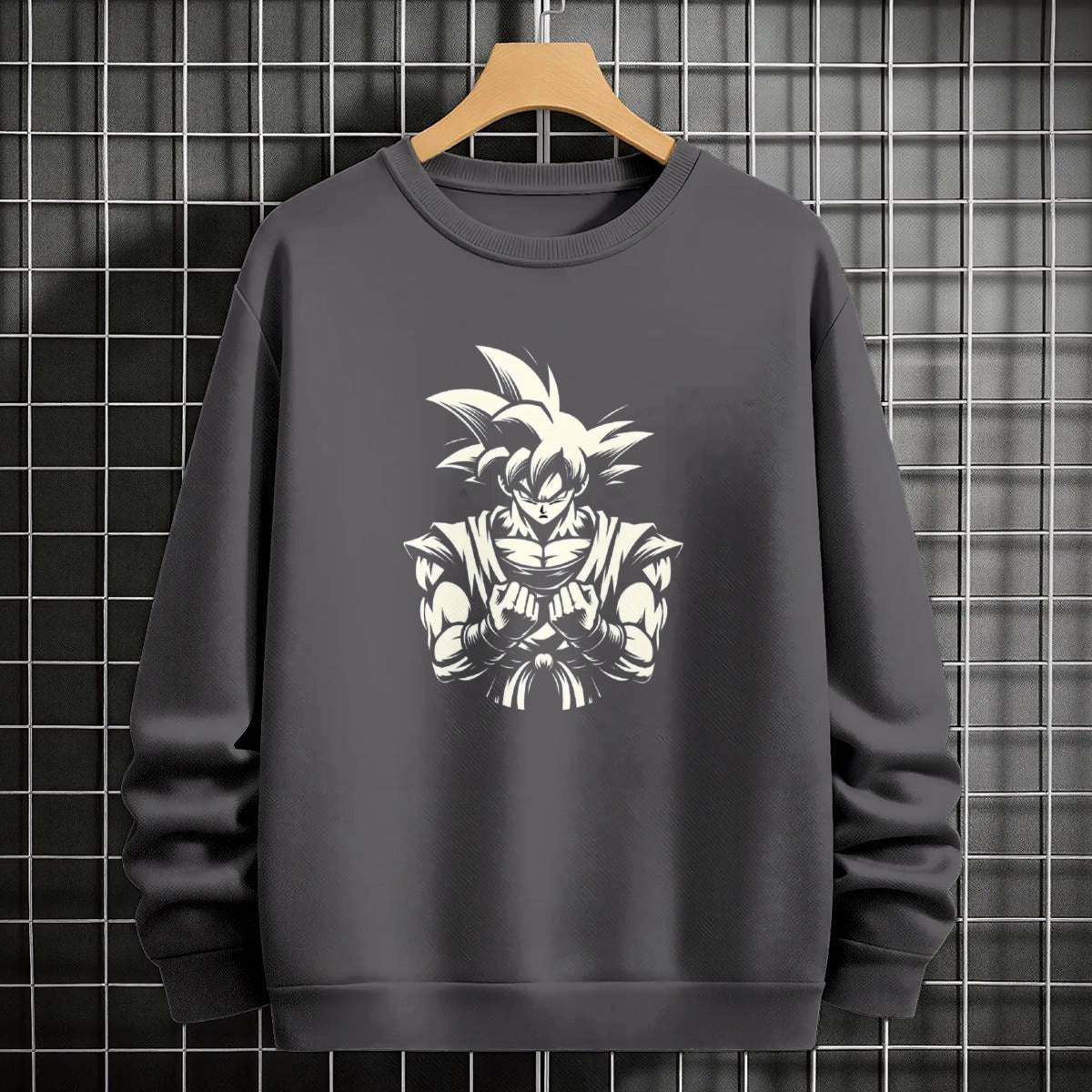 Black crewneck sweatshirt featuring Goku shadow silhouette with blue and pink neon aura and vertical Japanese text, flat lay on grey background.