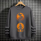 Black crewneck sweatshirt featuring Goku shadow silhouette with blue and pink neon aura and vertical Japanese text, flat lay on grey background.