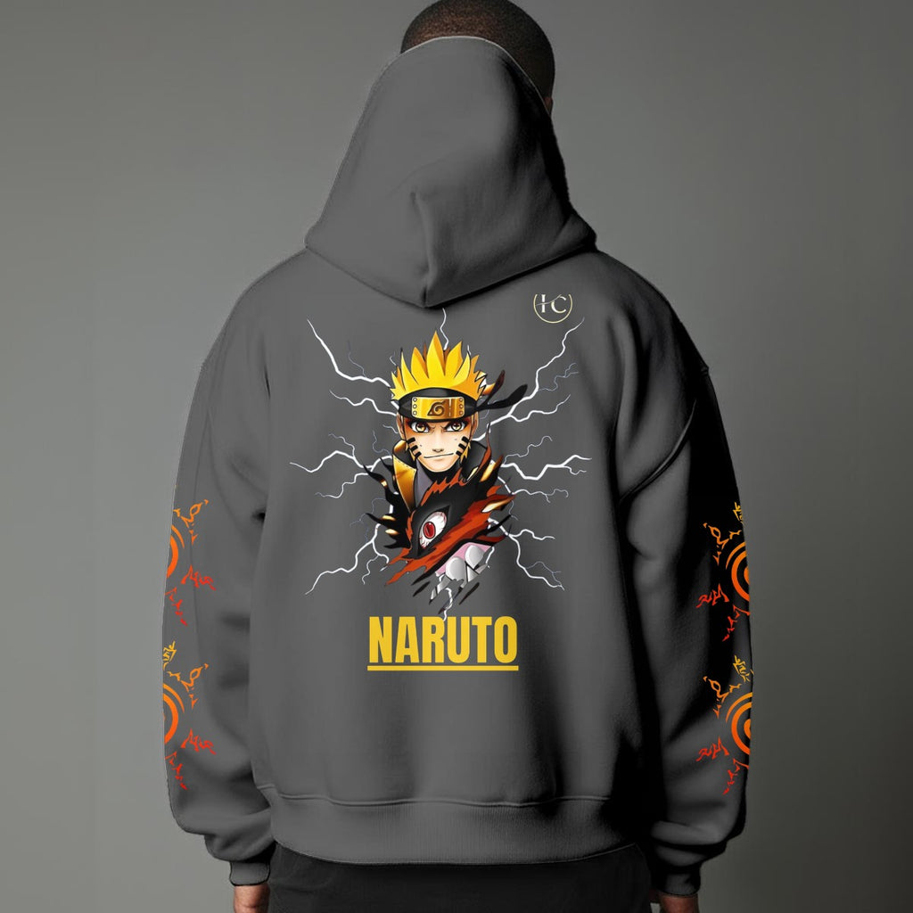 Black pullover hoodie featuring Naruto Uzumaki portrait on chest and vertical orange Japanese Kanji text on sleeves, worn by model on grey background.