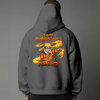 Black pullover hoodie featuring Naruto Uzumaki portrait on chest and vertical orange Japanese Kanji text on sleeves, worn by model on grey background.
