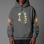 Black pullover hoodie with orange Goku silhouette on chest and vintage 1984 Dragon Ball graphics on sleeves, worn by model on grey background.