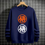 Black crewneck sweatshirt featuring two vertically stacked circular Dragon Ball Z 'Go' Kanji symbols (one orange, one white), flat lay on grey background.
