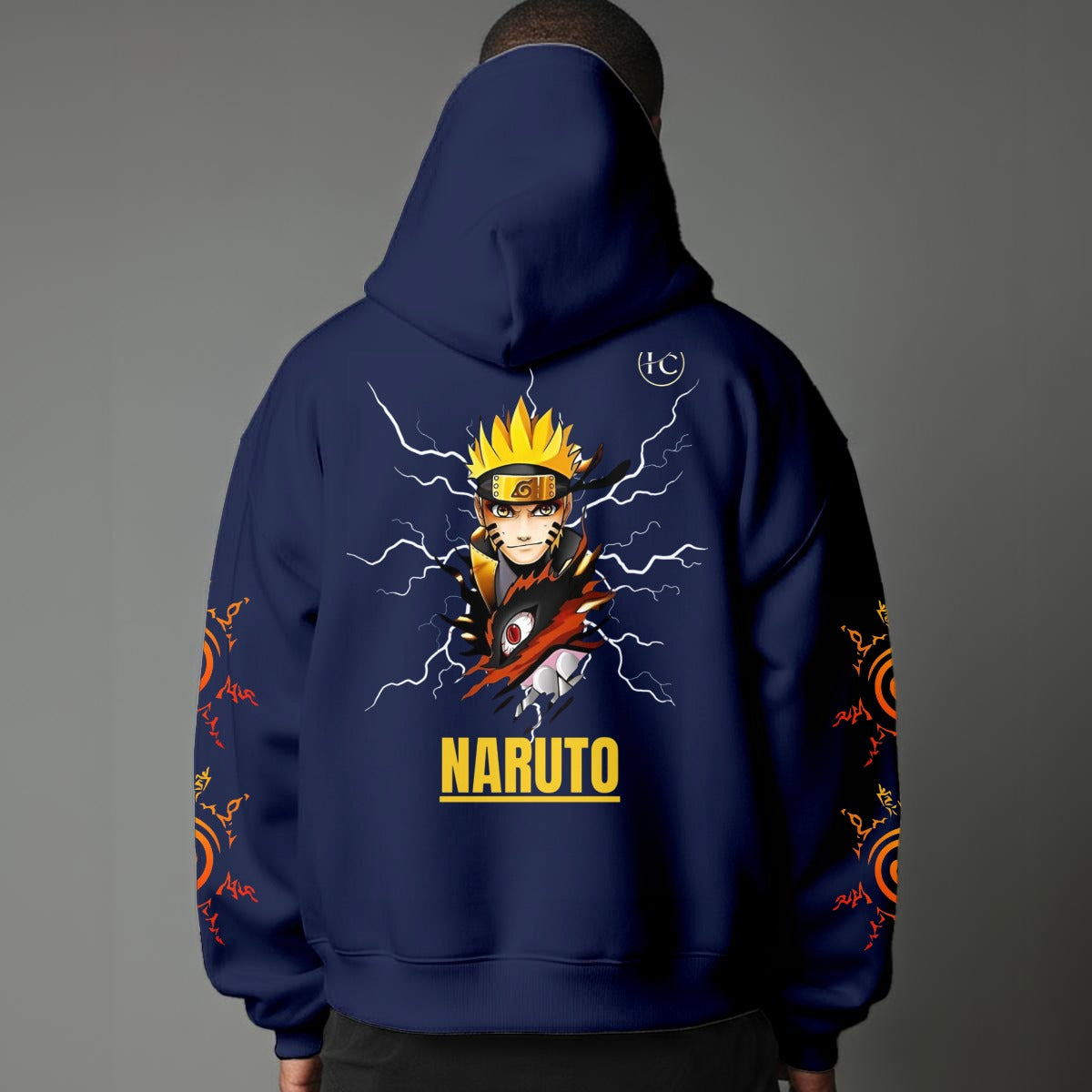 Black pullover hoodie featuring Naruto Uzumaki portrait on chest and vertical orange Japanese Kanji text on sleeves, worn by model on grey background.