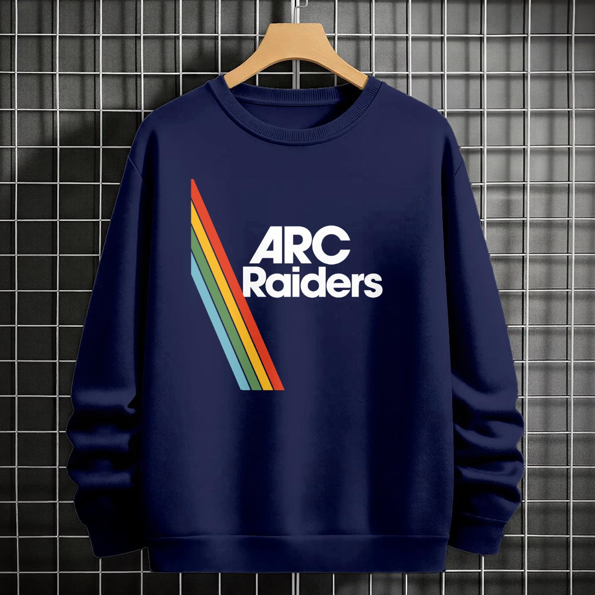 Navy blue sweatshirt with 'ARC Raiders' logo on a hanger against a tiled wall.