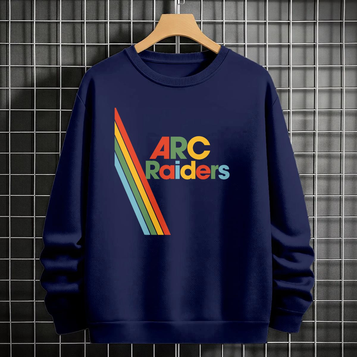 Navy blue sweatshirt with 'ARC Raiders' design on a hanger against a tiled wall.