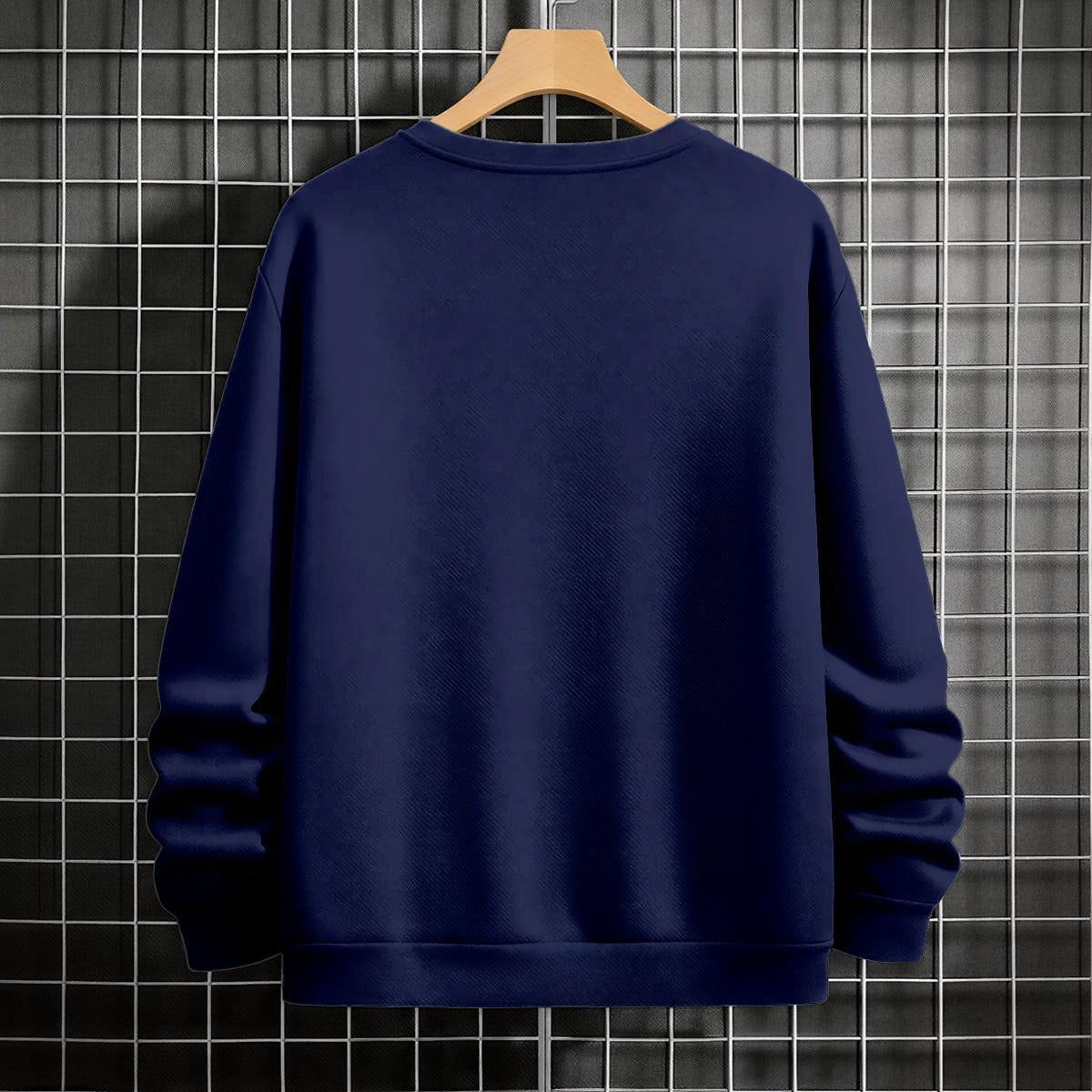 Navy blue sweatshirt on a wooden hanger against a tiled wall background