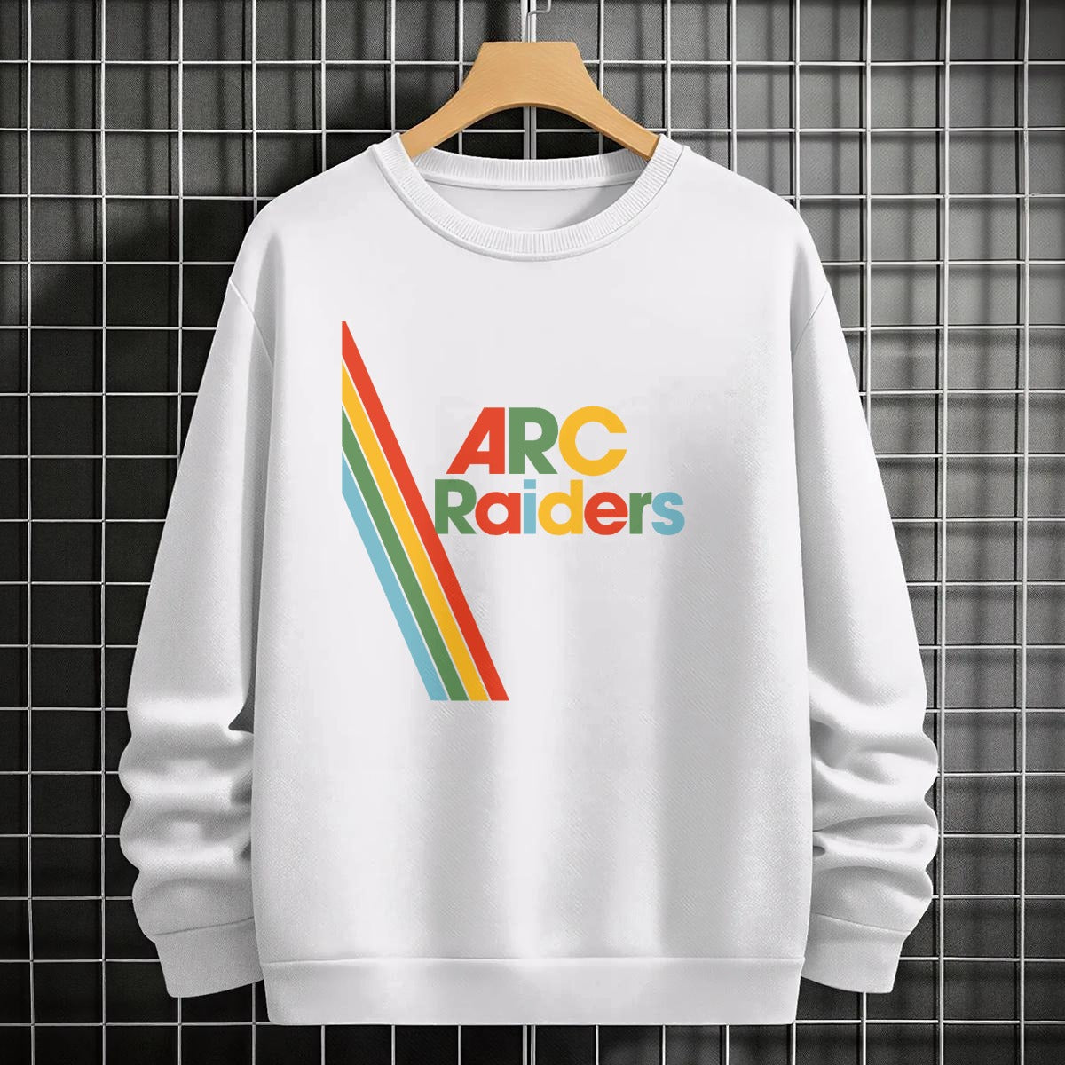 White sweatshirt with 'Arc Raiders' design on a hanger against a tiled wall.