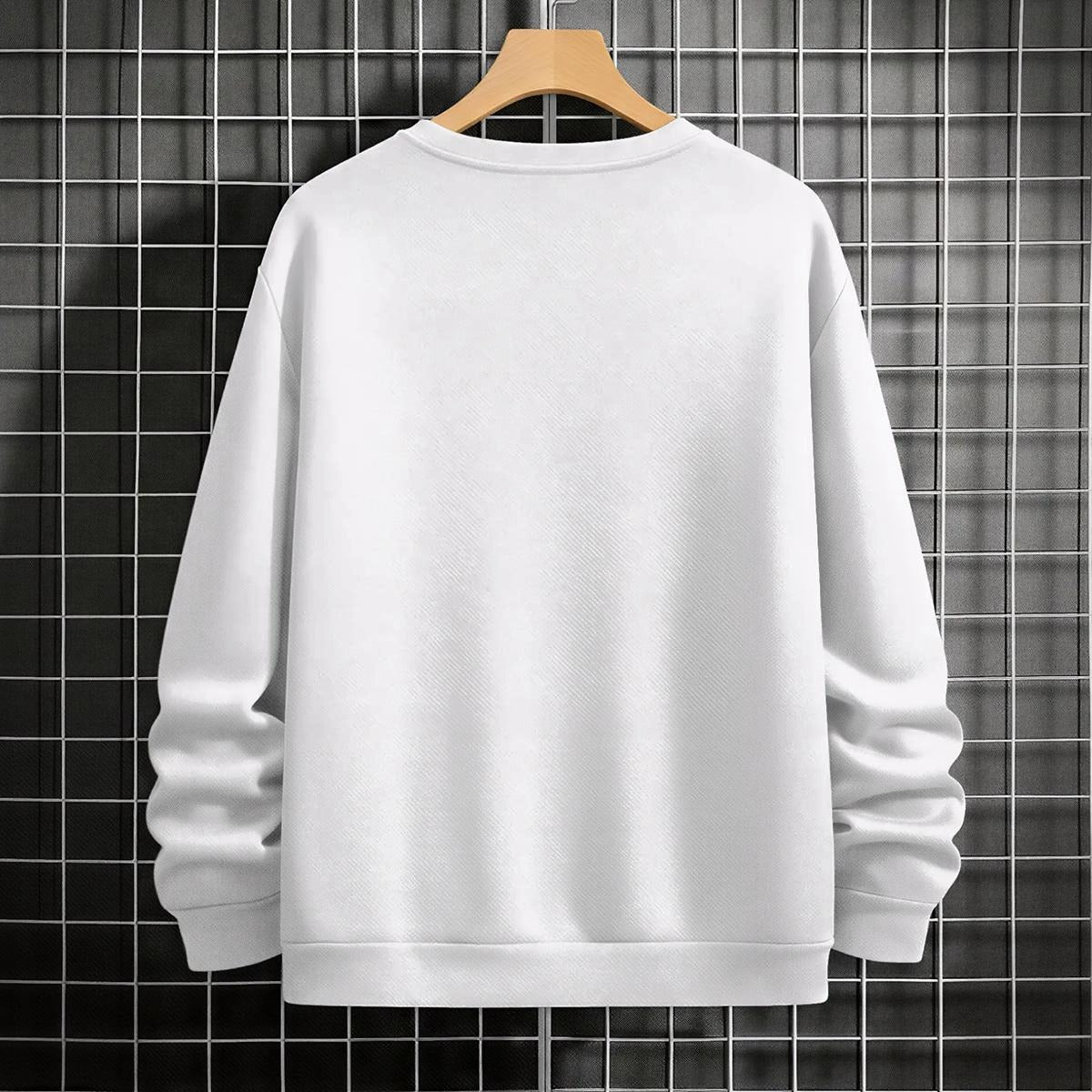 White sweatshirt on a wooden hanger against a grid-patterned wall.